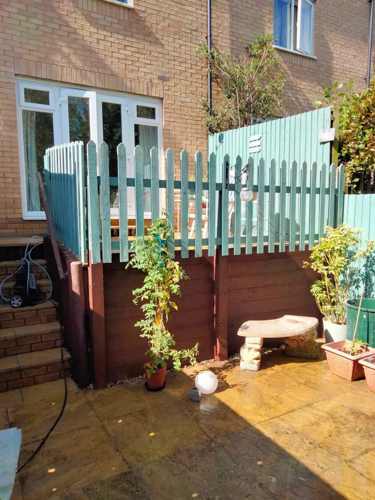 A striped lawn enclosed by a timber fence, with brick houses beyond, the kind of Norfolk garden DC Gardening Services quotes for