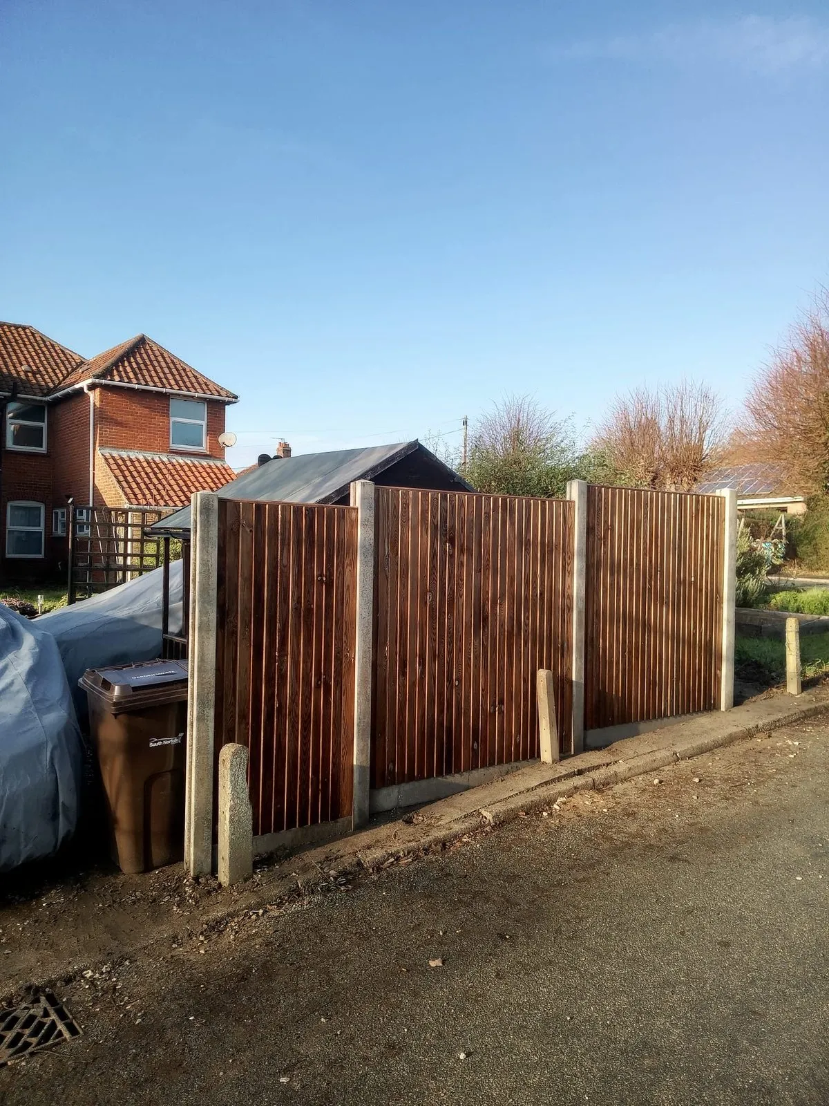 Timber decking and steps beside a green picket fence, with a pressure washer on the steps