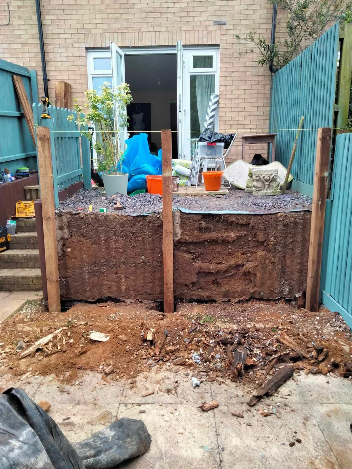A brick garden wall partly dismantled during repair, with loose bricks and a pier still standing